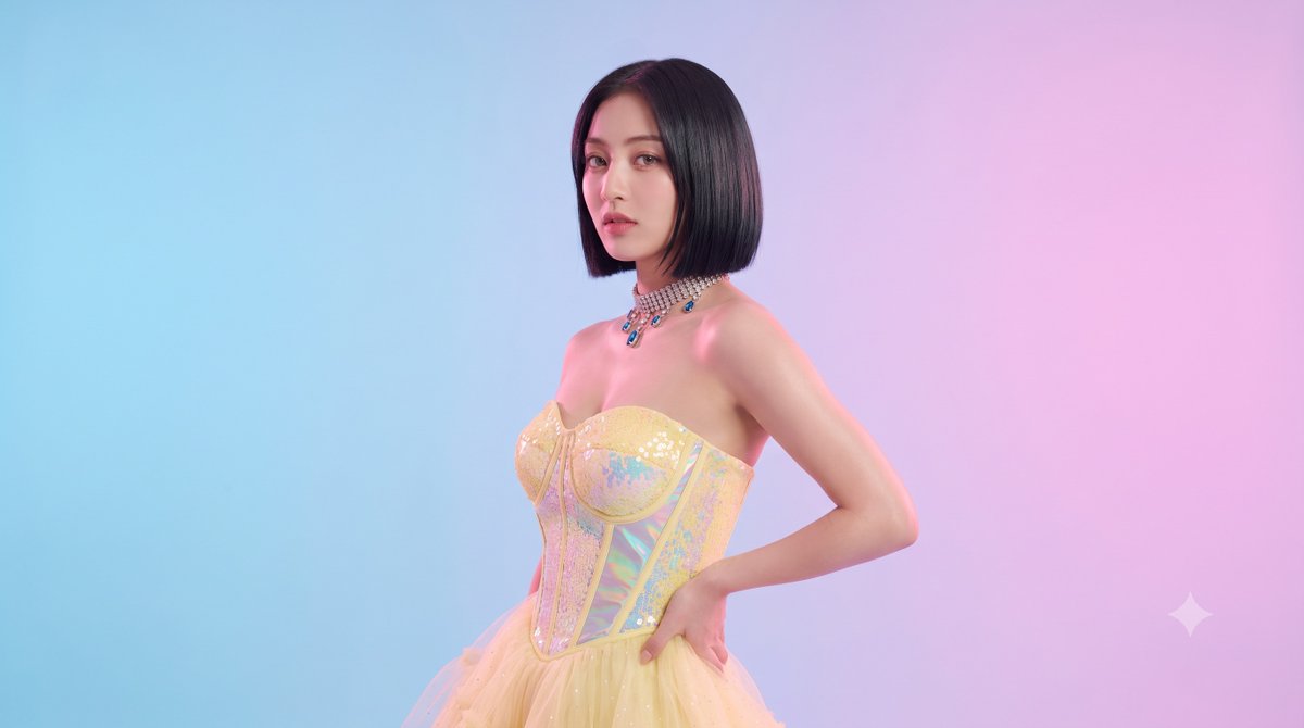 A full-length portrait of a woman in a pastel yellow sequined corset and tulle skirt, glancing back over her shoulder in a soft pink and blue studio. The…