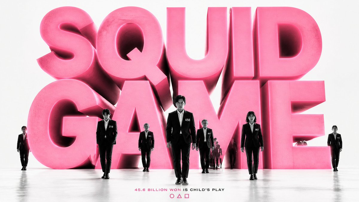 Oversized dark red letters fill the frame while a group of figures in matching formal suits walks toward the viewer across a plain white floor. Long shadows…
